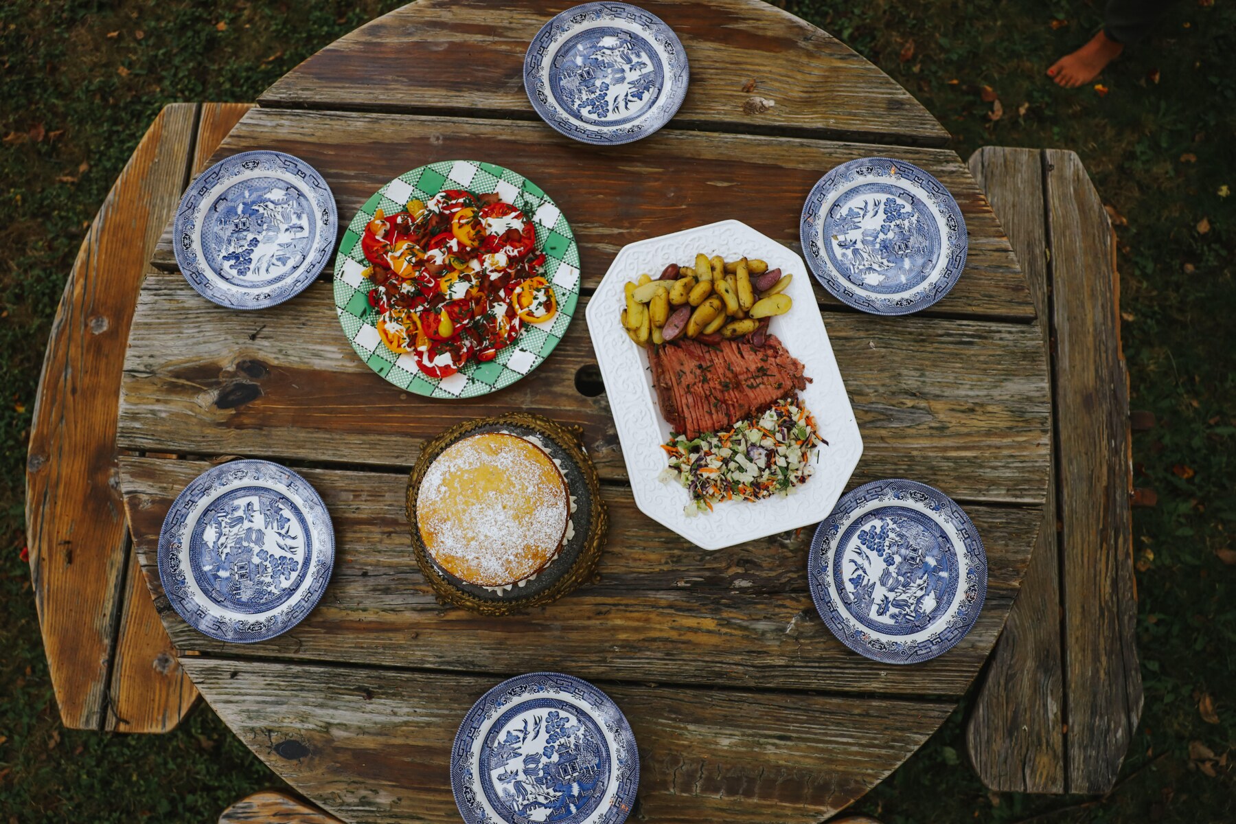 A colorful farm-table meal with cake, vegetables, potatoes, and ham